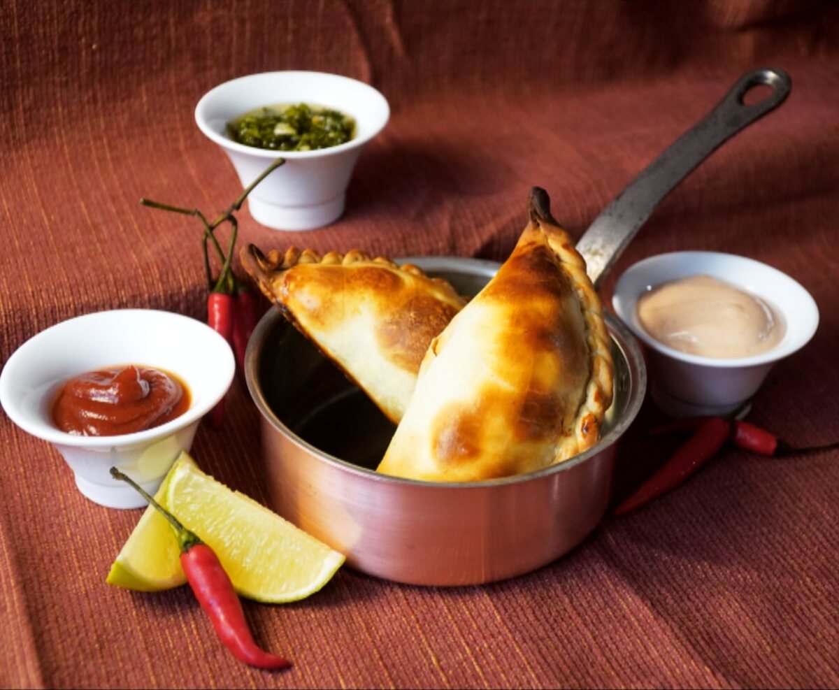 Empanadas in a copper pan with chimichurri and dipping sauces